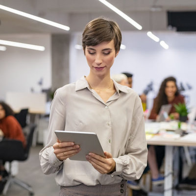 Happy young businesswoman using digital tablet in modern open office